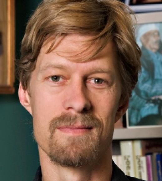 Man with goatee in front of a bookcase