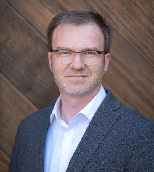 Man in front of wood-paneled wall