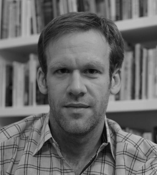 Black and white photo of man in front of bookshelf