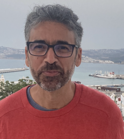 Man in red shirt, standing in front of the ocean