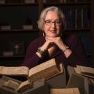 Woman leaning on her hands behind a pile of books
