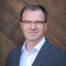 Man in front of wood-paneled wall