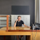 Man sitting at a large desk, answering an old fashioned phone