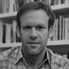 Black and white photo of man in front of bookshelf