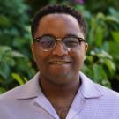Man in glasses standing in front of a greenery