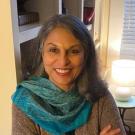 Woman in a teal scarf in front of a window