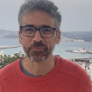Man in red shirt, standing in front of the ocean